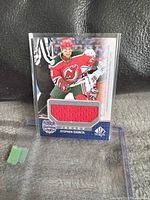 Front of Stephen Gionta hockey card with embedded red jersey piece and player action photo.