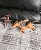 Two vintage figures on blanket; brown Pegasus and orange-black dragon with wings