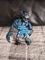 Blue and black Gorilla Alien figure standing upright on carpet with arms slightly bent, showing detailed blue highlights and biomechanical design.