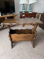 Front view showing the wood magazine stand with its wavy top surface and lower enclosed magazine storage.