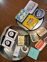 Photo of assorted tin boxes, two boxed Westclox alarm clocks, white night light on metal tray