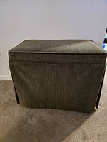 Front view of the upholstered foot stool showing textured green fabric and rectangular shape.