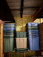 Multiple stacks of green, beige and blue bins in a storage area