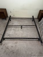 Assembled queen size metal bed frame with wheels, showing the full structure laid out flat on carpeted floor