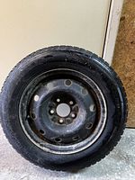 Single Ice Blazer snow tire mounted on a steel rim showing bolt holes and rim wear.