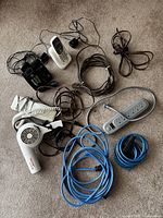 Two cordless phones with charging bases, one black, one white with answering machine, hair dryer, multiple cords and power bar on carpet