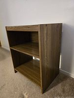 Front angle view of small wood finish shelf unit showing adjustable middle shelf and two fixed shelves below and above.