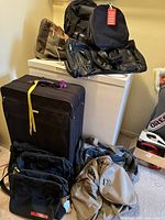 Overview of all bags and large black suitcase stacked near freezer