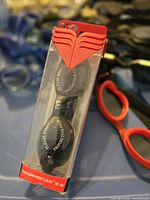 New pair of TYR Technoflex 2.0 swimming goggles in sealed box with protective film visible on lenses and red strap holder