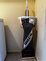 Oreck upright hotel vacuum with extra bags placed on vacuum with handle raised.