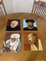 Four acrylic paintings on canvas laid out on a wooden table, showing elderly men of various ethnicities, each 12x10 inches, signed by artist.
