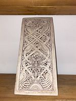 Front view of the off-white ceramic panel showing detailed carved pattern.
