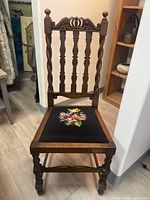 Front view of traditional wooden accent chair showing detailed carved wooden back and cross stitch floral seat upholstery.