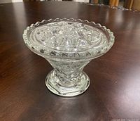 Top-front angle of the clear crystal flower holder showing the starburst pattern and multiple holes on a scalloped rim.