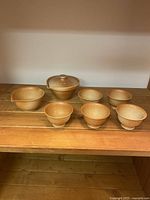 Front view of the tan ceramic Japanese tea set showing all 7 pieces on wooden surface under neutral lighting