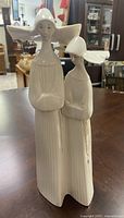 Front view of the Lladro porcelain figurine showing two nuns in ivory with detailed robes and serene expressions on a wooden table.