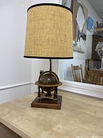 Full view of the MCM astrological globe table lamp with beige fabric shade and wooden base.