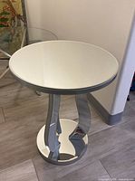 Front angle view of the round table showing the reflective curved chrome mirrored legs and circular base.
