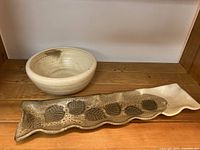 Photo showing pottery bowl and decorative tray with leaf pattern, wooden surface background