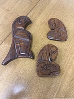 Set of three carved indigenous art pieces on wooden surface