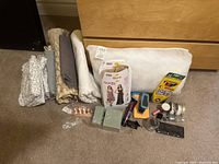 Photo taken showing entire lot with fabric, pillow insert, sewing patterns, various sewing and craft tools and accessories arranged on floor.
