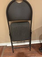 Folded grey fabric and metal folding chair showing backrest and folded seat