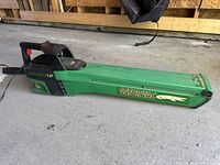 Side view of green GatorVac VIP electric leaf blower/vacuum showing brand logos and power cord attached