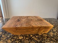 Square thick wooden serving platter showing wood grain on top surface and sides, held on countertop.