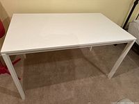 Front view of large white MDF desk showing the flat rectangular desk surface and four legs.