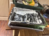 Black plastic paint trays with white paint residue stacked
