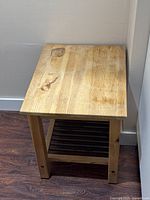 Front view of small wooden side table showing wood grain, square legs, and stained top surface.