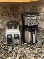 Photo showing the T-Fal 2-slice toaster and Black+Decker coffee maker side by side on a granite kitchen countertop.
