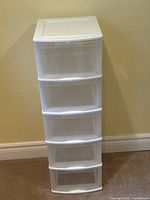 Front view of white 5-drawer plastic organizer showing all drawers and top surface.