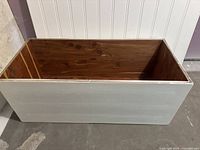 Rectangular wooden box without lid, showing white painted exterior and natural wood interior