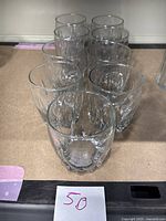 Nine clear glass Anchor Hocking Central Park Double Old Fashioned glasses arranged in three rows on a shelf