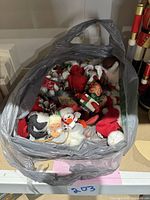 Photo showing assorted soft fabric Christmas ornaments in a plastic bag including elves, angels, snowman, and others in red, white, green color scheme.