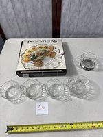 Four small Arcoroc crystal bowls arranged with original egg platter box and a glass bowl with metal base on a table, showing clear starburst cut glass design.