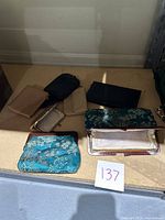 Shows full lot of nine assorted coin purses in different sizes, colors and materials, including Asian themed ones with embroidery and others made of leather or faux leather.