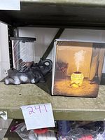 Terracotta elephant incense burner with cylindrical glass cover beside its box showing humidifier producing mist with warm globe light.