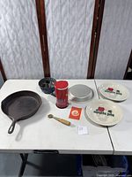 Full lot with cast iron skillet, apple pie dishes, cake pans, cheese grater, pie crimper on table