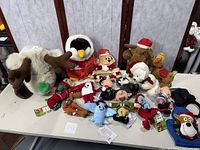 Wide view of assortment of Christmas plush toys including animals and characters like reindeer, penguin, Santa, elves and more