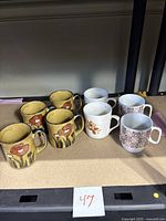 All eight coffee mugs grouped on a shelf.