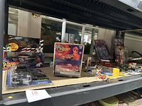 Shelf showing Dale Earnhardt collectible cars in original boxes along with small figurines and a TV remote.