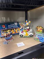 Winnie the Pooh and Mickey & Friends snow globes and figurine displayed alongside the boxed 10 light Mickey & Friends tree trimmer set