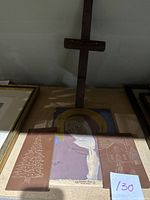 Wooden cross holder standing with two etched leather pieces and wooden painted panel laying in front.