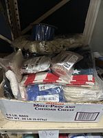 Box containing packs of decorative lace and ribbons on spools and loose bundles with different patterns and colors, along with some ropes