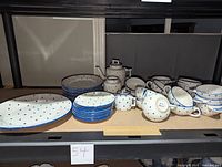 Full view of all dishes arranged on a shelf showing all types of pieces in the lot