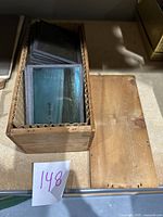 Wooden box opened to reveal stacked magic lantern slides inside, showing the box details and slide arrangement