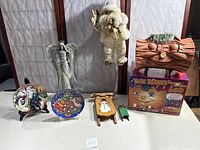 Full view of lot including untested talking Yule log with original box, two small wooden decorative sleds, two commemorative Avon plates on stands, Santa door hanger, and metal angel figure.