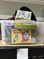 Photo of a clear plastic bin containing multiple Tasmanian Devil Taz items including a boxed pencil sharpener, pins, and other collectibles.